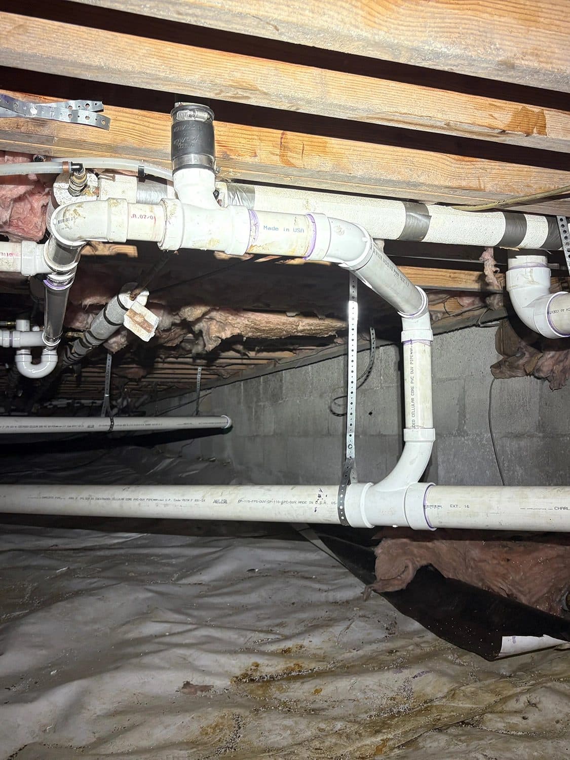 New PVC drain piping installed in a crawl space